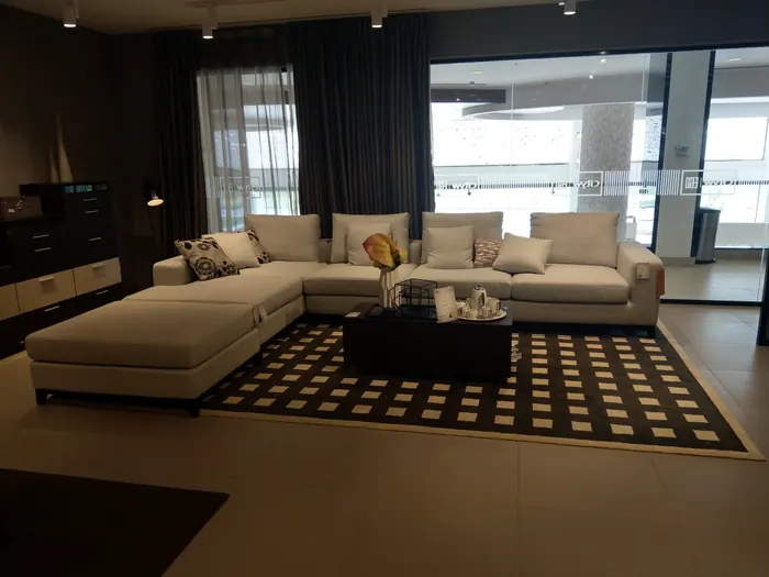 Canapé d'angle beige et table basse sombre sur tapis graphique